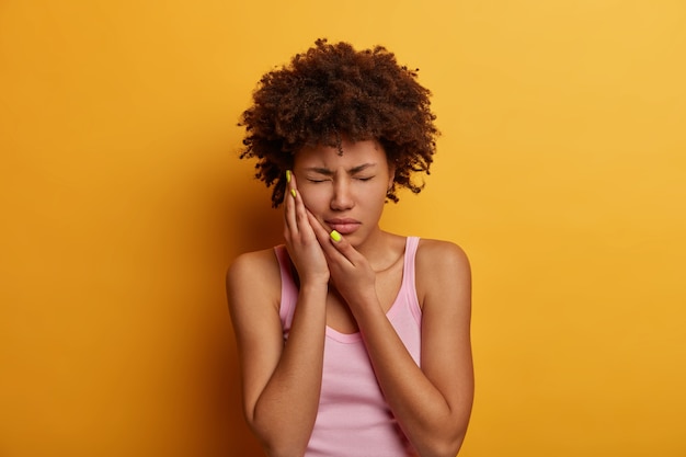 Une femme mécontente à la peau foncée souffre de maux de dents