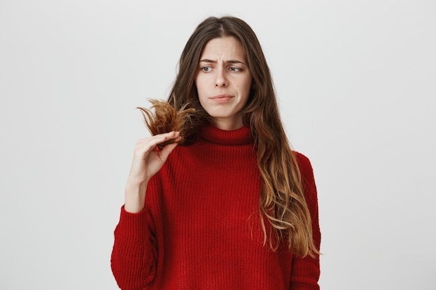 Femme mécontente regardant les pointes fourchues de cheveux