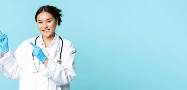 Femme médecin asiatique souriante thérapeute pointant du doigt le coin supérieur gauche montrant des publicités médicales