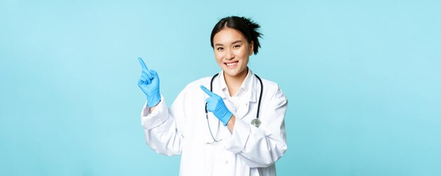 Femme médecin asiatique souriante thérapeute pointant du doigt le coin supérieur gauche montrant des publicités médicales