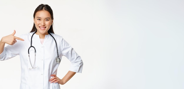 Femme médecin asiatique souriante véritable travailleur médical professionnel pointant du doigt elle-même portant des médicaments