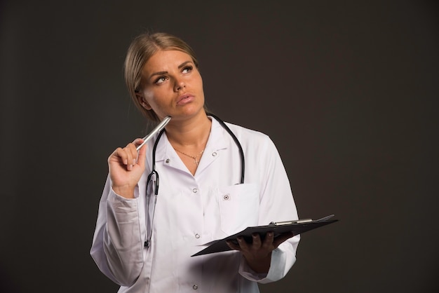 Femme médecin blonde avec un stéthoscope et un carnet de reçus.