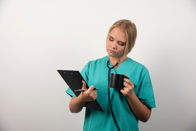 Femme médecin avec coupe en regardant le presse-papiers.