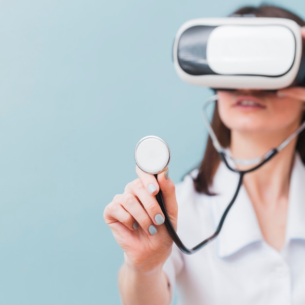 Femme médecin défocalisé à l'aide d'un casque de réalité virtuelle et d'un stéthoscope