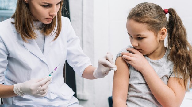 Femme médecin donnant une seringue sur le bras d&#39;une fille malade