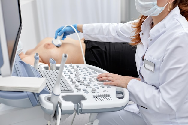 Femme médecin donne au patient une échographie abdominale féminine. scanner à ultrasons entre les mains d'un médecin.