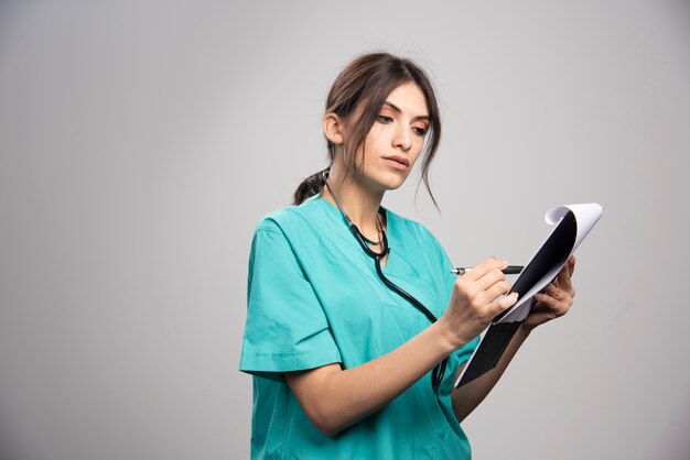 Femme médecin, écrire des notes sur le presse-papiers