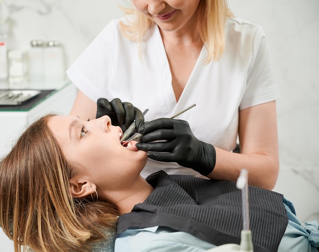 Femme médecin examinant les dents du patient dans une clinique dentaire