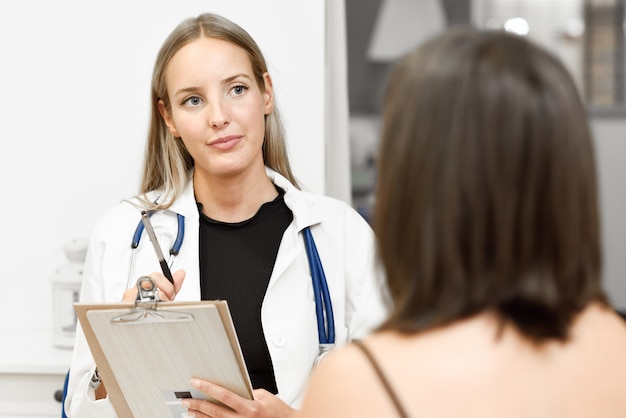 Femme médecin expliquant le diagnostic à sa jeune femme patiente.