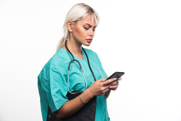 Femme médecin faisant un appel téléphonique sur une surface blanche