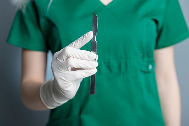 Femme médecin avec un gant en caoutchouc tenant un scalpel