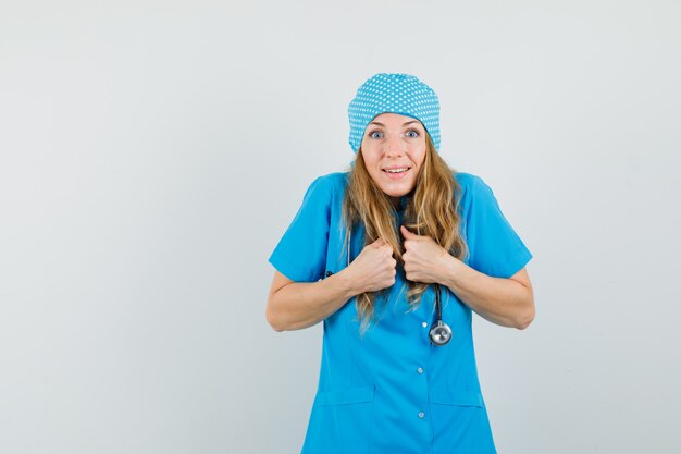 Femme médecin gardant les poings sur la poitrine en uniforme bleu et à l'air heureux.