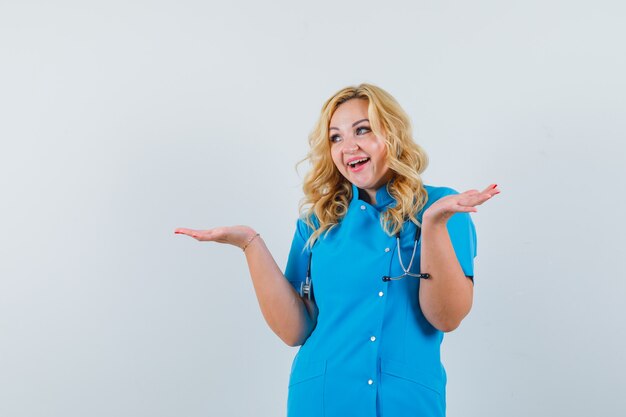 Femme médecin en levant les mains tout en exprimant ses sentiments en uniforme bleu et à la jovial