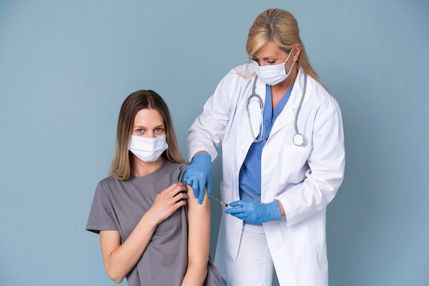 Femme médecin avec masque médical donnant un vaccin à une femme