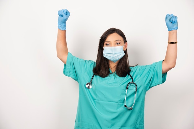 Femme médecin avec masque montrant ses poings sur fond blanc. Photo de haute qualité