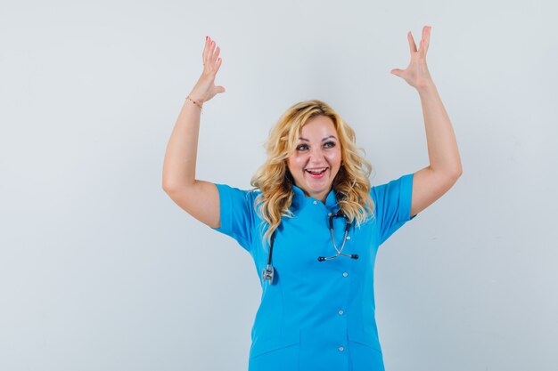 Femme médecin montrant le geste gagnant en uniforme bleu et l'air heureux,