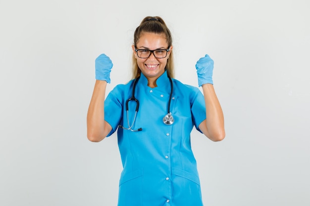 Femme médecin montrant le geste gagnant en uniforme bleu