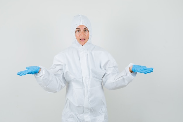 Photo gratuite femme médecin montrant un geste impuissant en tenue de protection, gants et à la confusion.