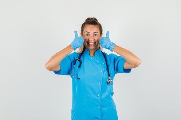 Femme médecin montrant les pouces vers le haut en uniforme bleu