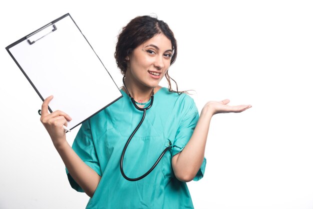 Femme médecin montrant le presse-papiers vide avec un stylo et un stéthoscope sur fond blanc. Photo de haute qualité