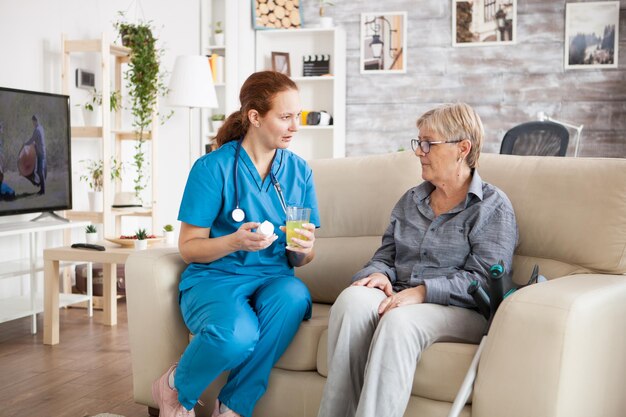 Femme médecin parlant avec une femme âgée dans une maison de retraite à propos de nouvelles pilules médicamenteuses