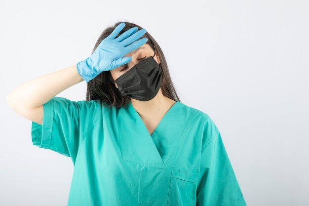 Femme médecin portant un masque médical noir et tenant la tête.