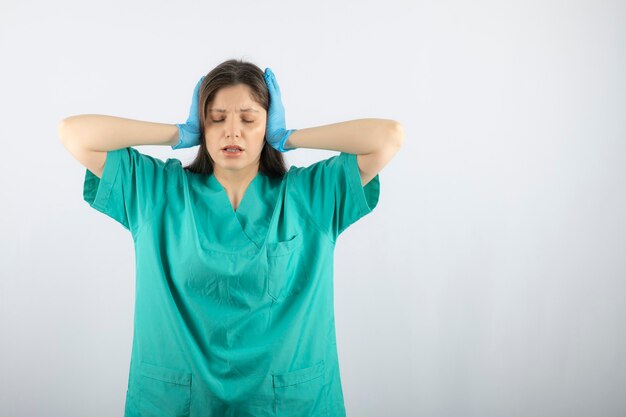 Femme médecin portant un uniforme médical vert et tenant la tête.