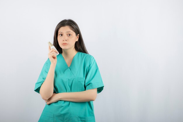 Femme médecin portant un uniforme vert tenant une seringue sur blanc.