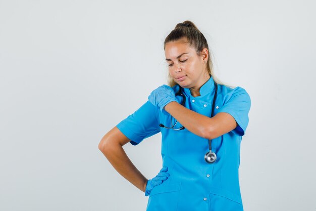 Photo gratuite femme médecin posant tandis que les mains sur l'épaule et la taille en uniforme bleu