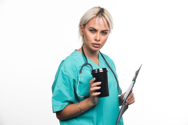 Femme médecin prenant une pause avec une tasse de café sur une surface blanche