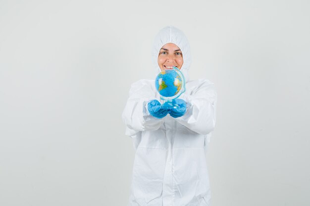 Femme médecin présentant le globe terrestre en combinaison de protection