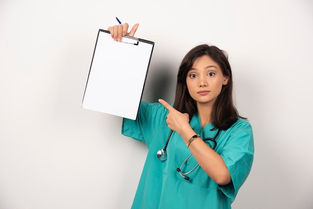 Femme médecin avec presse-papiers de pointage stéthoscope sur fond blanc. Photo de haute qualité