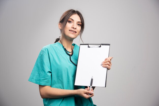 Femme médecin, à, presse-papiers, regarder appareil-photo