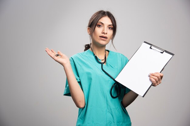 Femme médecin, à, presse-papiers, regarder appareil-photo