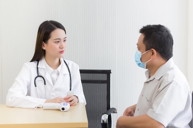 Une femme médecin professionnelle asiatique parle avec un patient de sa douleur et de ses symptômes