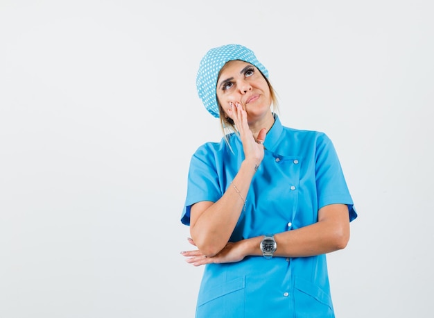 Femme médecin recherchant en uniforme bleu et à la réflexion