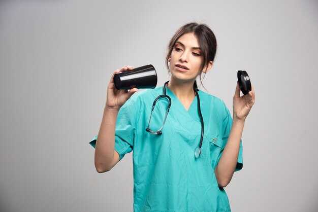 Femme médecin à la recherche de café sur fond gris