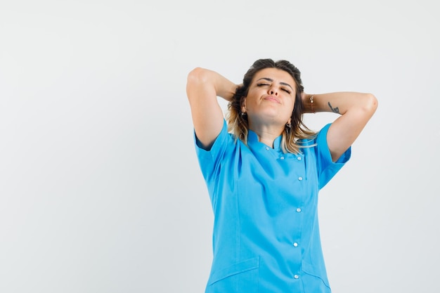 Femme médecin serrant la tête dans les mains en uniforme bleu et l'air détendu