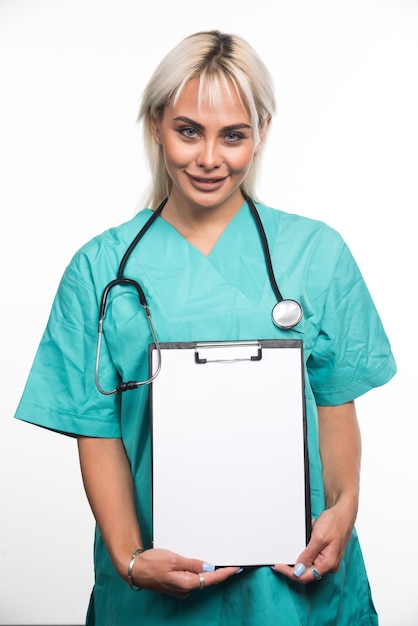 Femme médecin souriante tenant un presse-papiers sur fond blanc. Photo de haute qualité