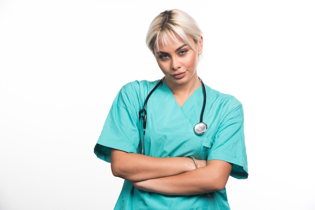 Femme médecin avec stéthoscope croisant les bras sur une surface blanche