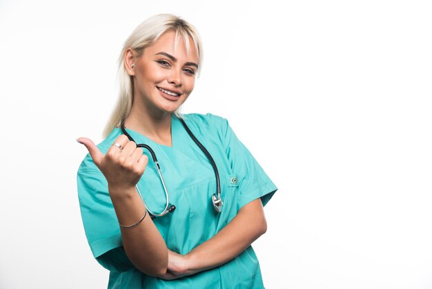 Femme médecin avec stéthoscope doigt pointé sur fond blanc. Photo de haute qualité