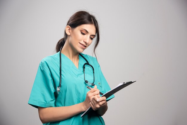 Femme médecin avec stéthoscope écrit sur le presse-papiers