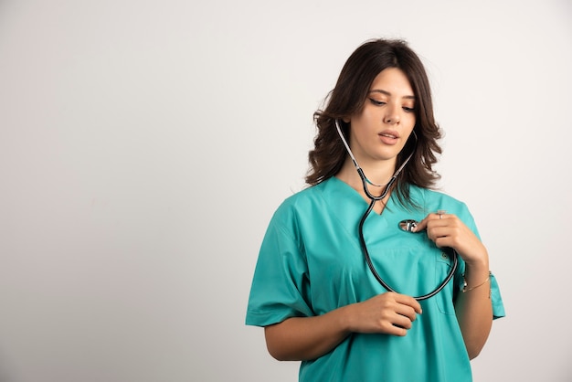 Femme médecin avec stéthoscope posant sur blanc.