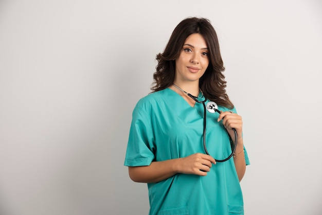 Femme médecin avec stéthoscope posant sur blanc.