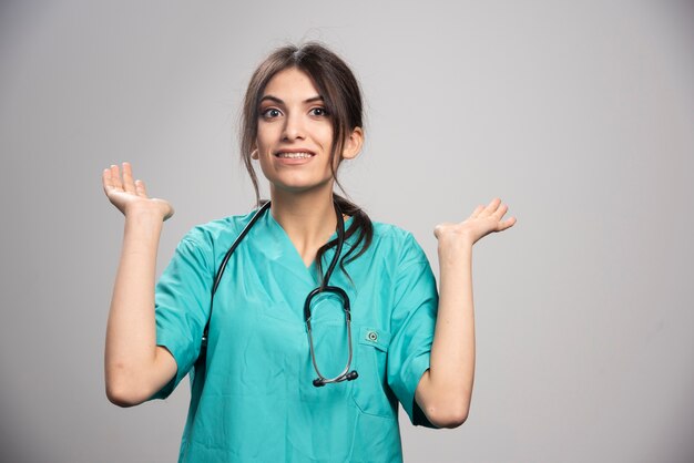 Femme médecin avec stéthoscope posant sur fond gris