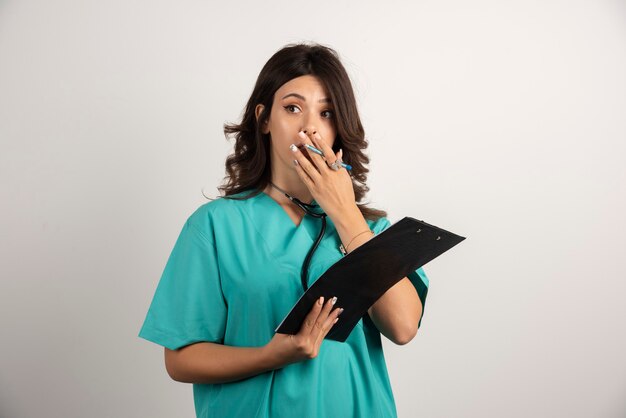 Femme médecin avec stéthoscope surprise après avoir lu les journaux.