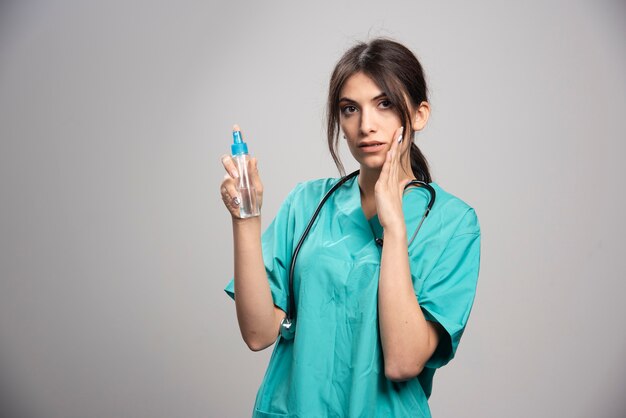 Femme médecin avec stéthoscope tenant un flacon pulvérisateur