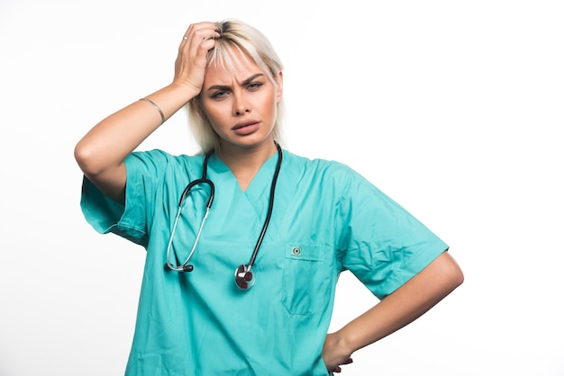 Femme médecin avec stéthoscope tenant ses cheveux sur fond blanc. Photo de haute qualité