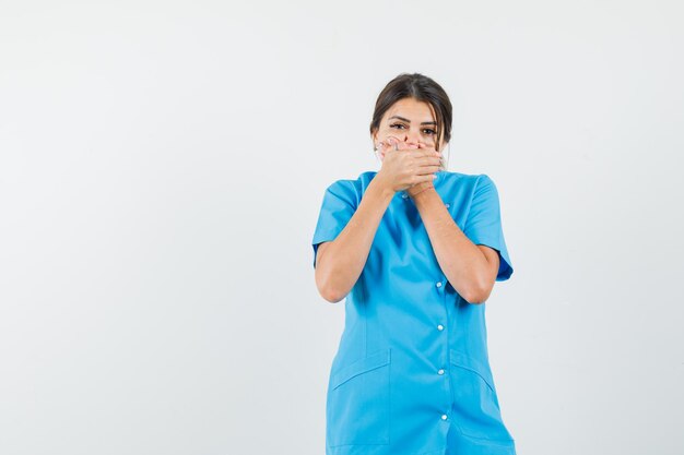 Femme médecin tenant la main sur la bouche en uniforme bleu et à la peur