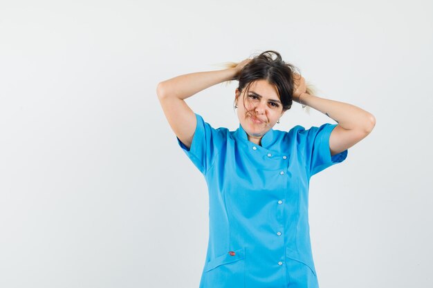 Femme médecin tenant la main sur la tête en uniforme bleu et à la belle